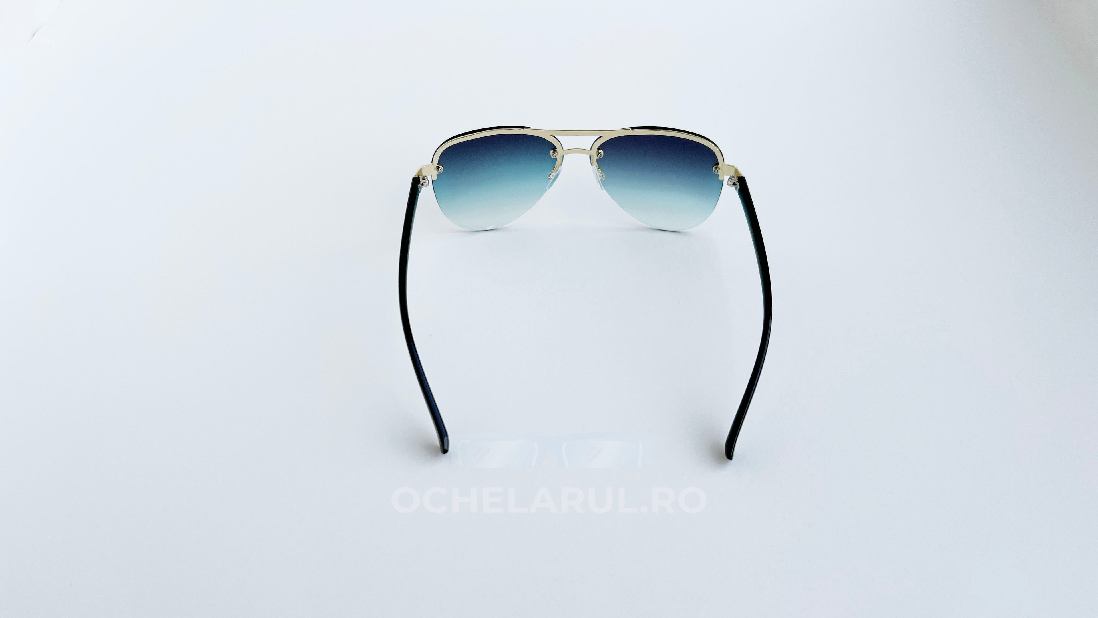 Ochelari de soare Aviator cu lentile albastre degrade și rame negre cu detalii aurii, eleganți și moderni.