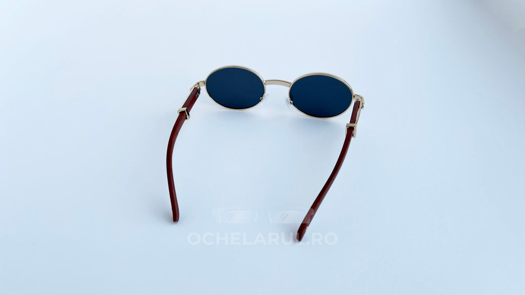 Ochelari de soare Cartier Giverny Style cu rame aurii și brațe maro, lentile negre ovale, design elegant.