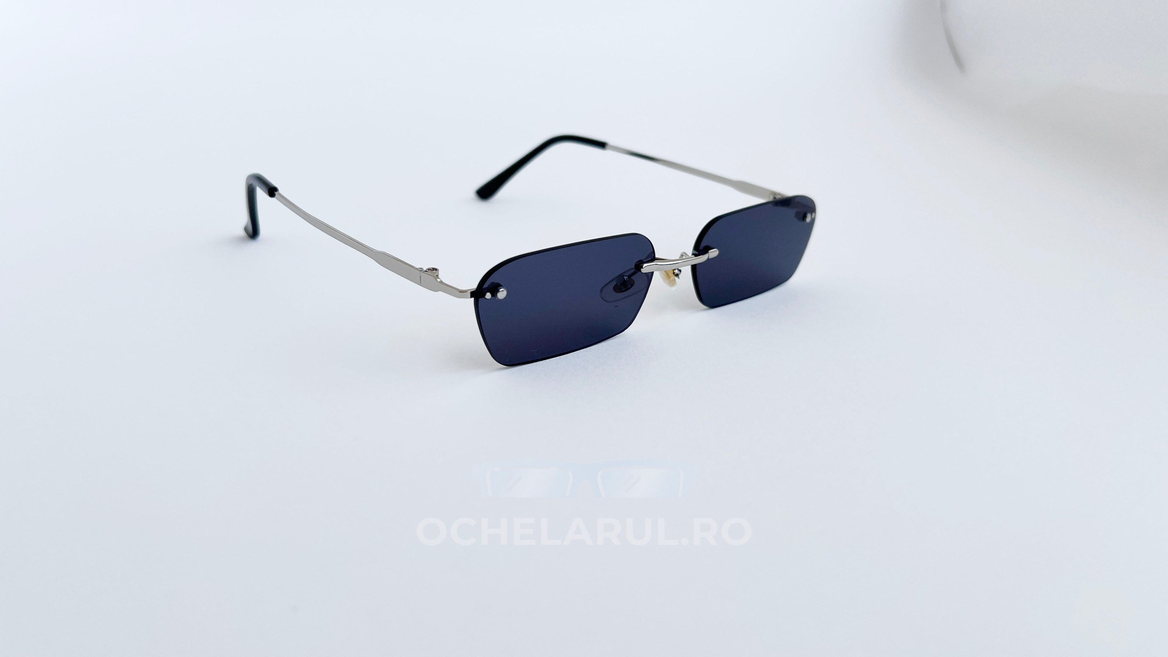 Ochelari de soare Dreptunghiulari Rimless cu lentile negre și brate argintii subțiri, design modern.