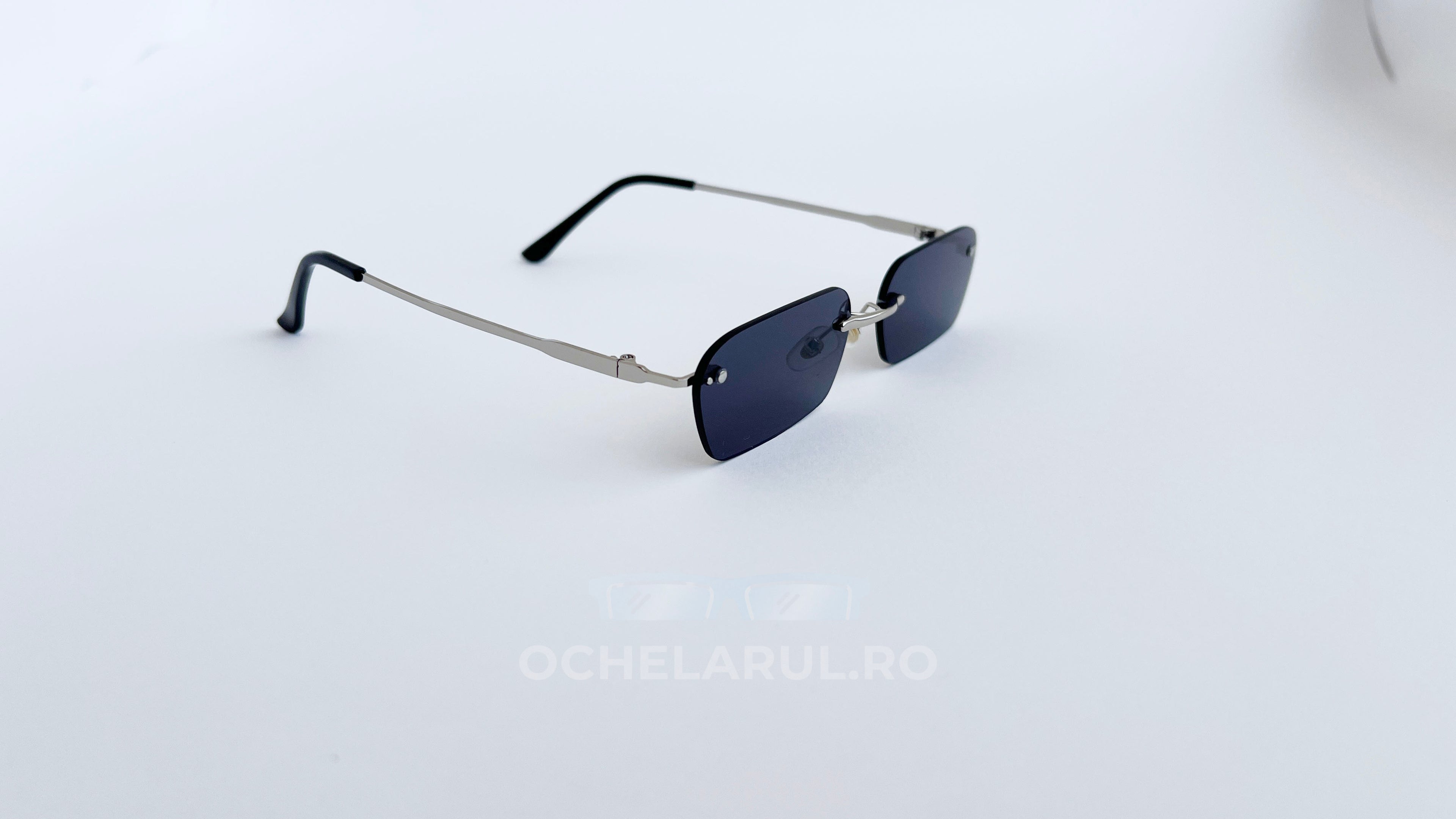 Ochelari de soare Dreptunghiulari Rimless cu lentile negre și brațe argintii, design minimalist și elegant.