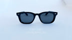 Ochelari de soare Moscot Klutz Style cu rame negre și lentile închise la culoare pentru protecție optimă.