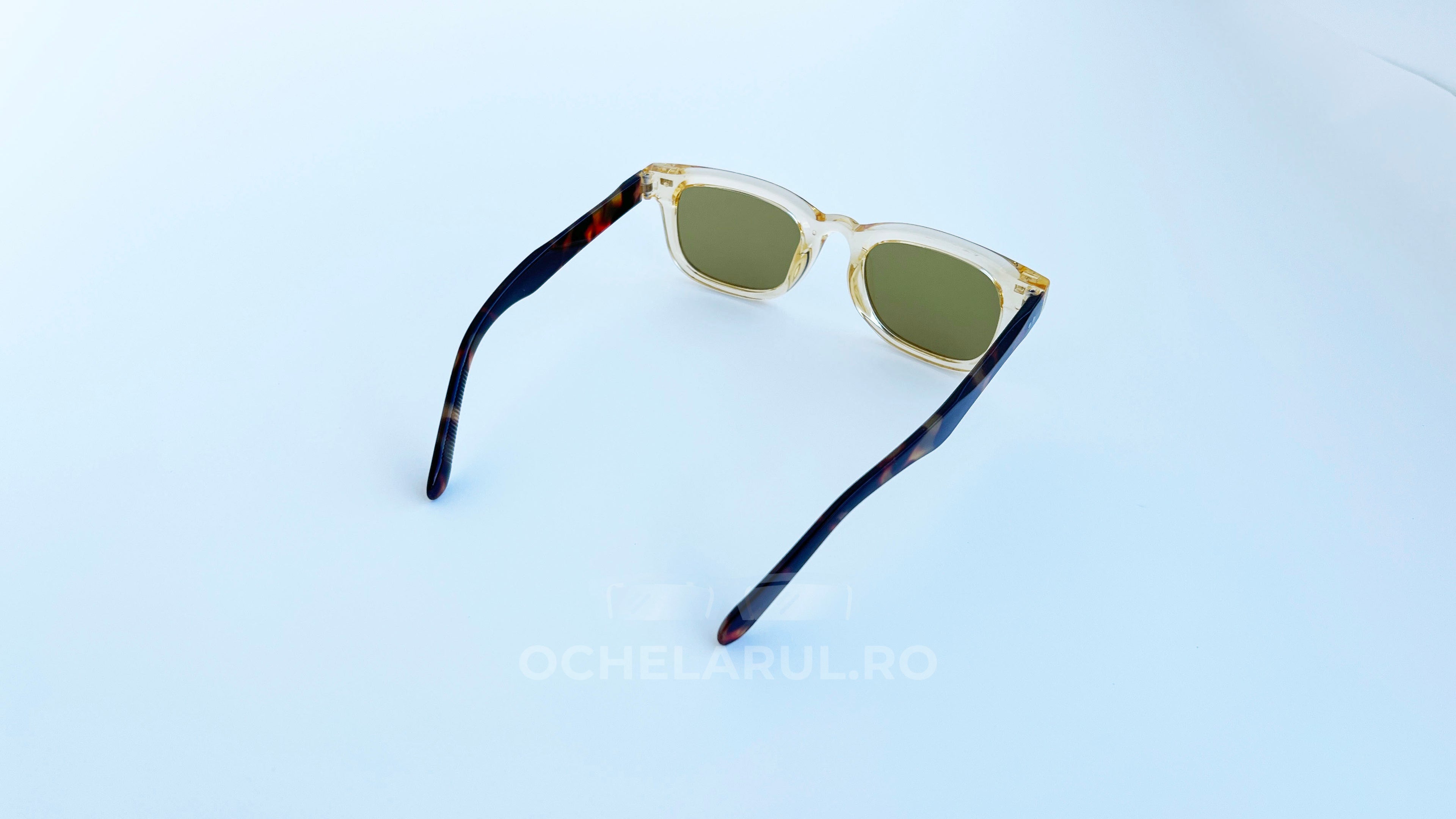 Ochelari de soare Moscot Klutz Style cu rame bej transparente și brațe în nuanțe de tortoise, lentile maro, design masculin modern și elegant.