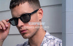 Bărbat purtând ochelari de soare Ochelari Moscot Lemtosh Style - Polarizați Fotocromatici cu rame negre și lentile gri.