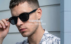 Bărbat purtând ochelari de soare Moscot Lemtosh Style cu rame negre și lentile întunecate, stil modern și elegant.