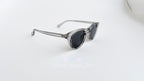 Ochelari de soare Oliver Peoples Style cu rame gri transparente și lentile gri, model pentru bărbați.