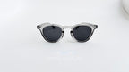 Ochelari de soare Oliver Peoples Style cu rame gri transparente și lentile întunecate, design elegant pentru bărbați.