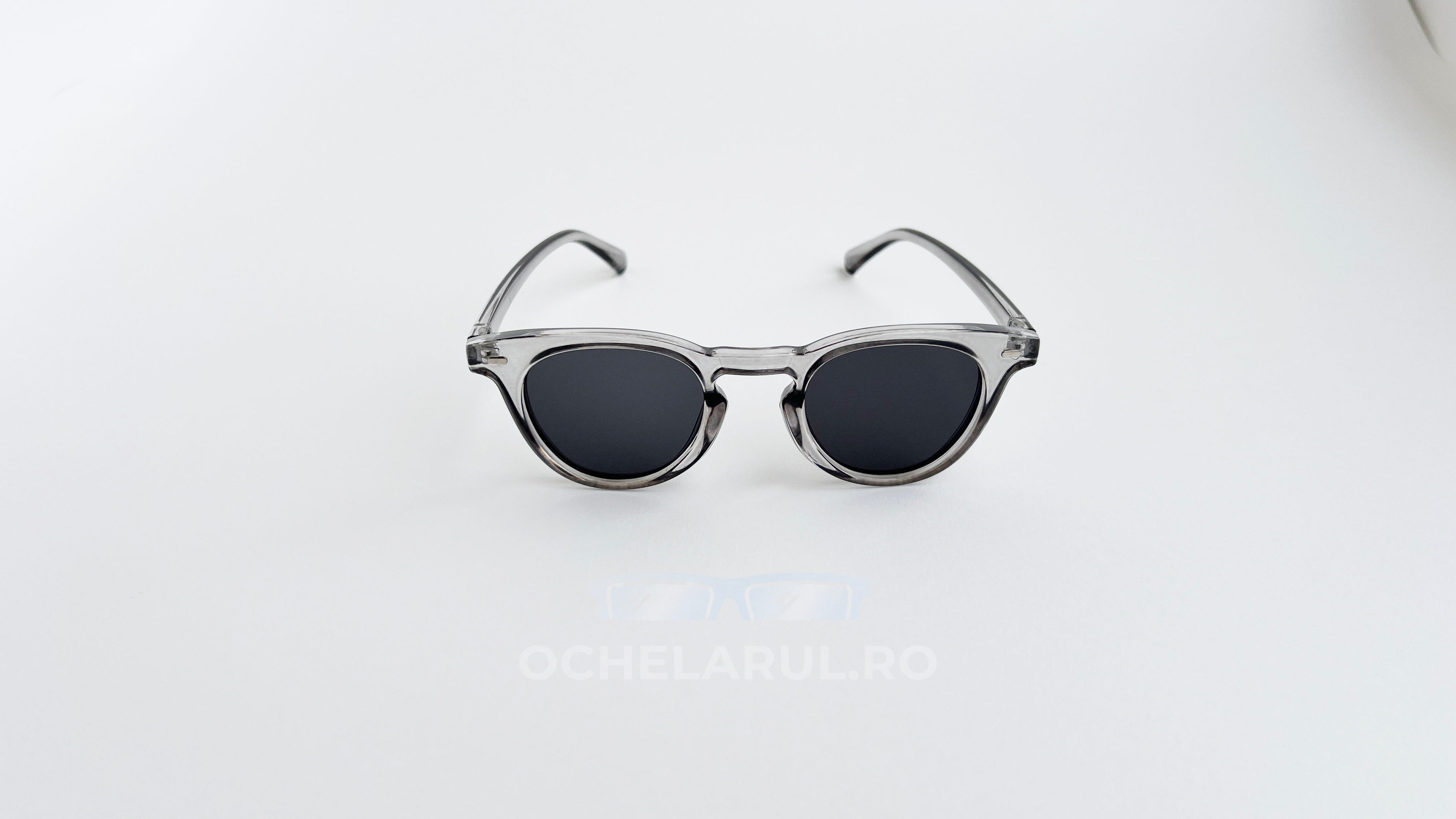 Ochelari de soare Oliver Peoples Style cu rame gri transparente și lentile gri închise pentru bărbați.