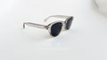 Ochelari de soare Moscot Lemtosh Style cu rame gri transparente și lentile negre pentru protecție UV.
