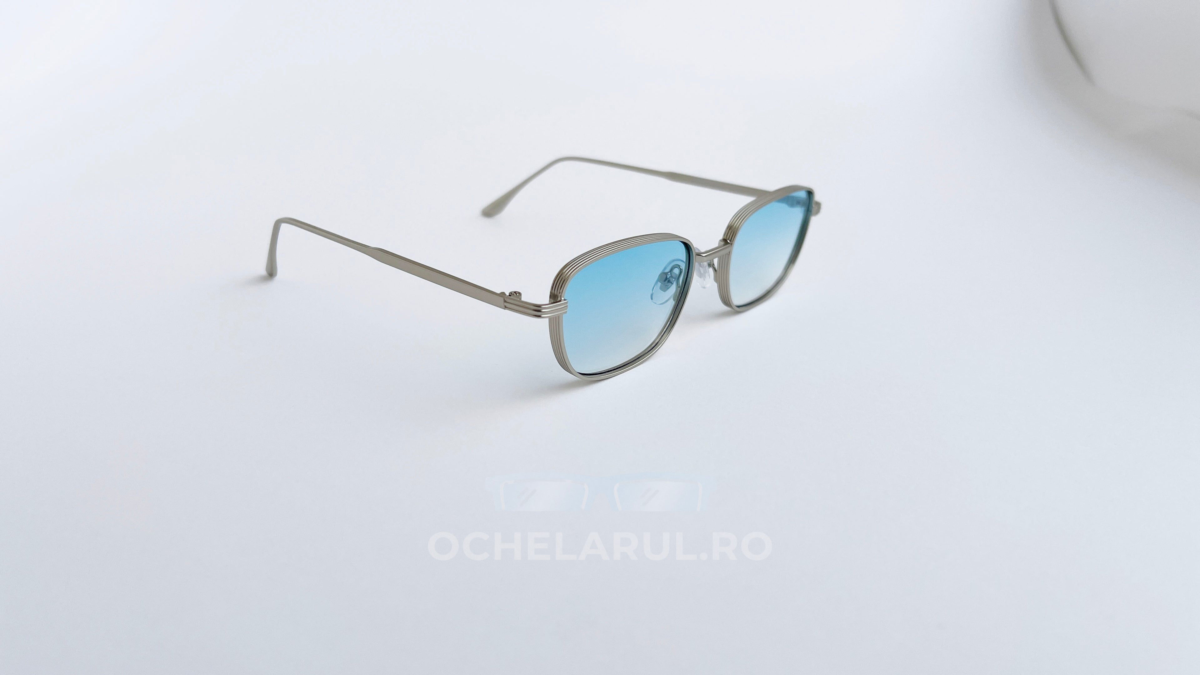 Ochelari de soare Retro Rectangulari cu rame argintii subțiri și lentile albastre degrade, design modern și elegant.