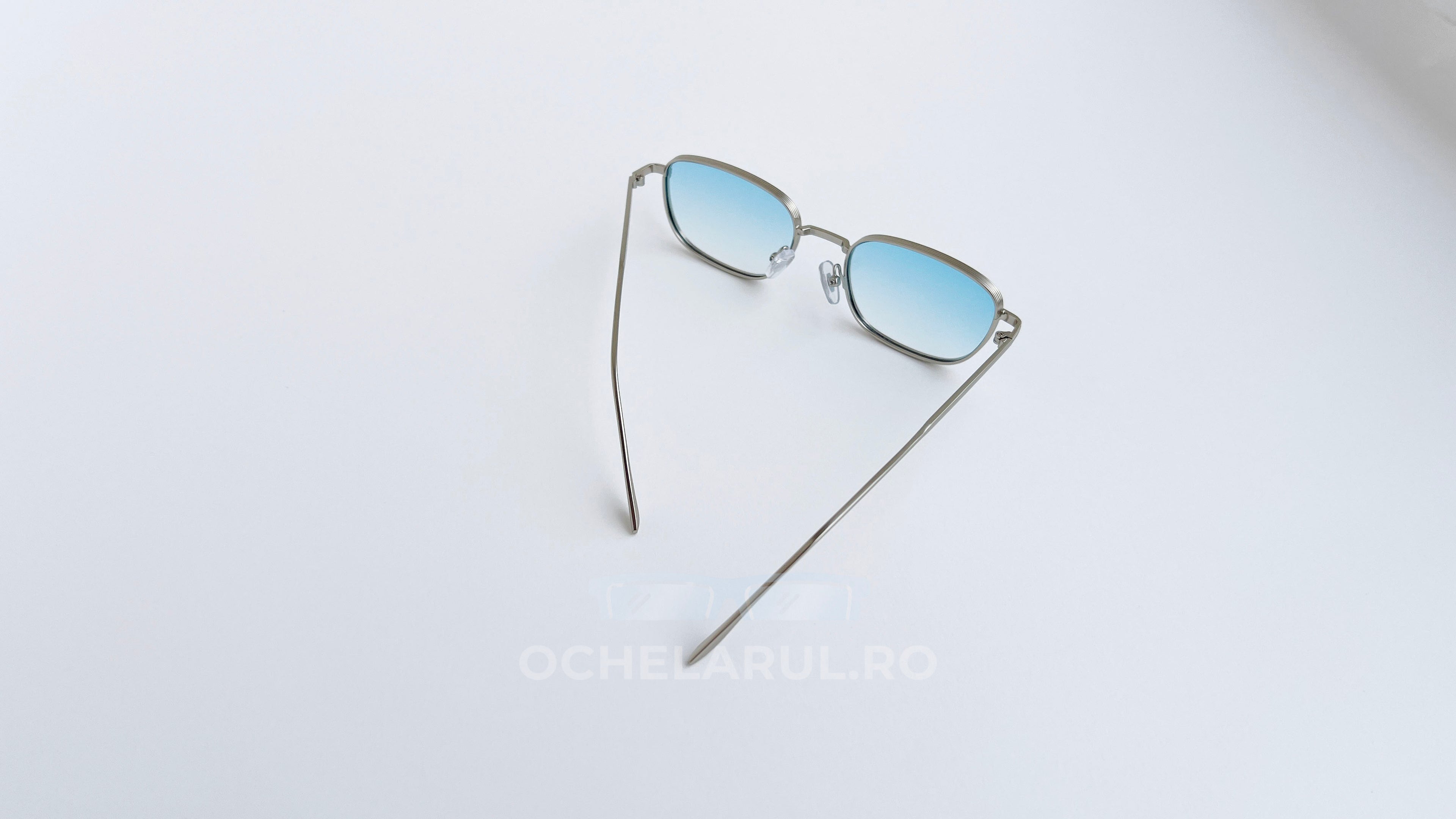 Ochelari de soare Retro Rectangulari cu rame argintii subtiri și lentile albastre degrade, design minimalist modern.