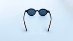 Ochelari de soare Rotunzi Retro Style cu rame negre și brațe în nuanțe de tortoise, lentile întunecate, model clasic pentru un stil vintage și elegant.