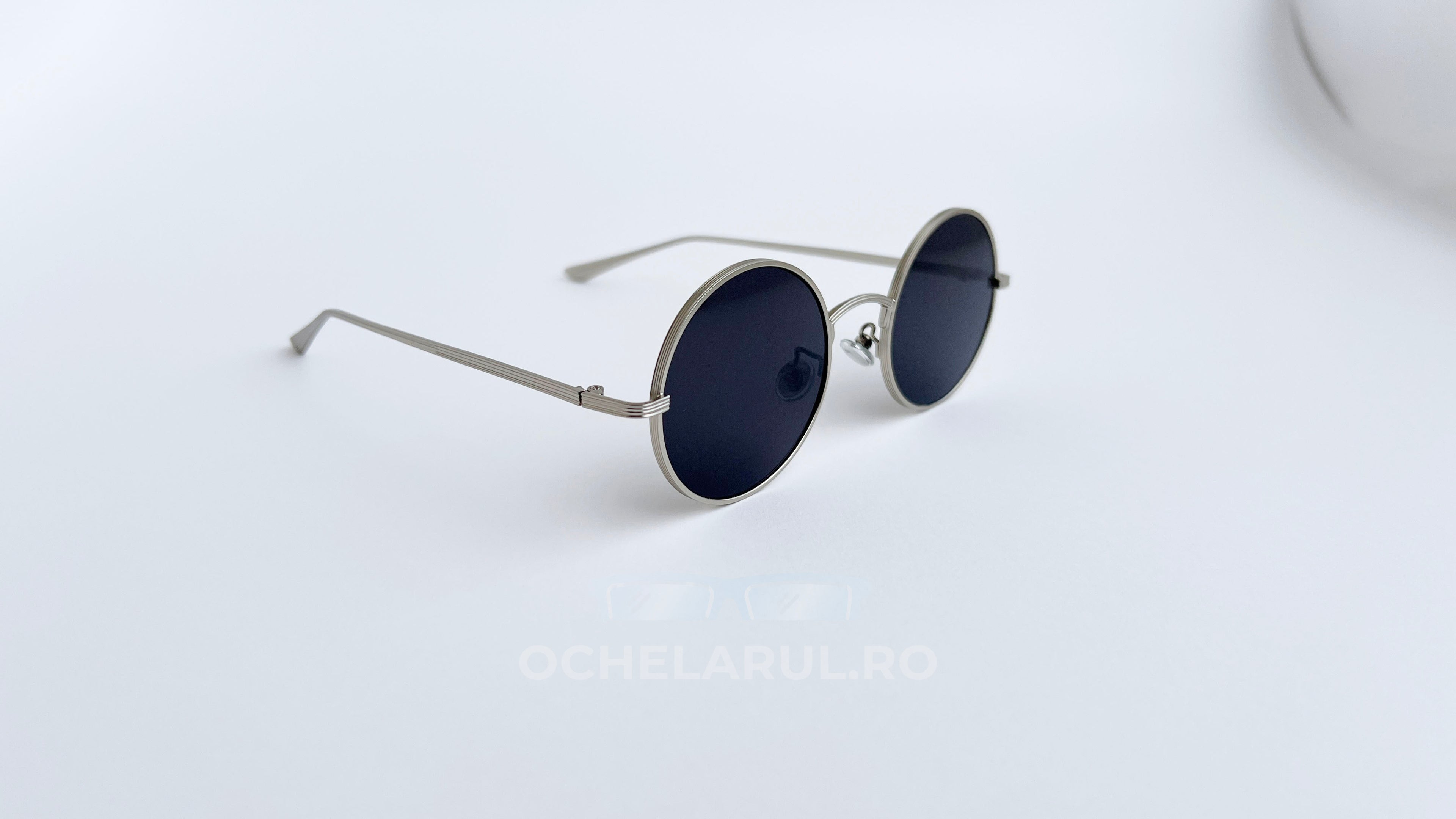 Ochelari de soare Rotunzi cu rame argintii subțiri și lentile negre, un model elegant și modern potrivit pentru bărbați care caută protecție și stil.