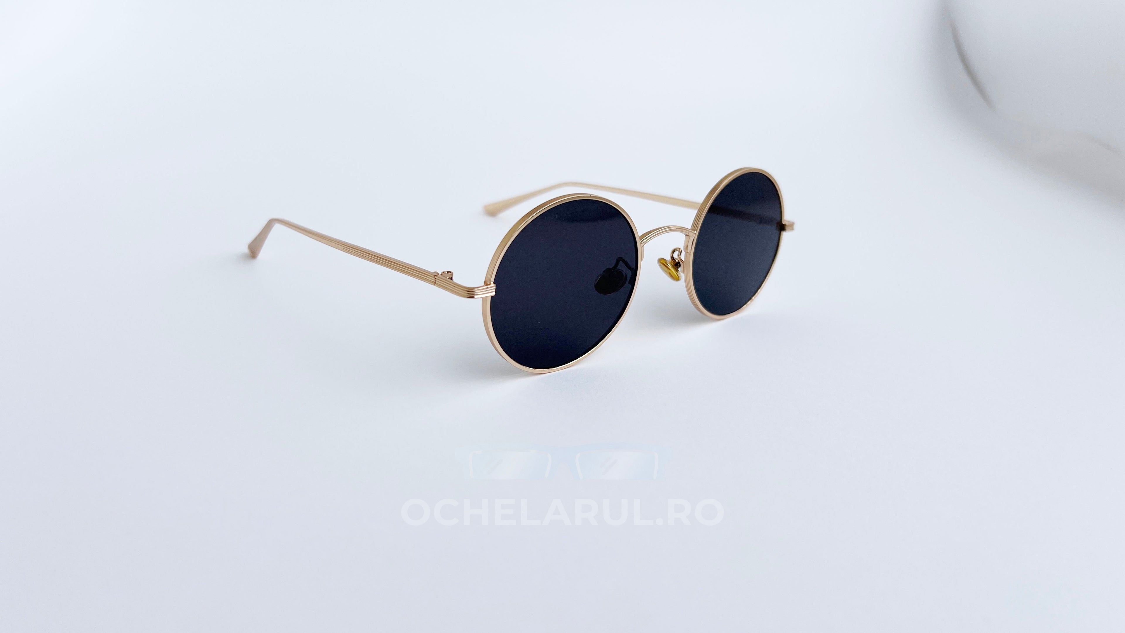 Ochelari de soare Rotunzi cu rame aurii și lentile negre, design elegant și minimalist, ideali pentru protecție solară și stil urban modern.