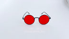 Ochelari de soare Rotunzi cu ramă neagră subțire și lentile roșii intense, design modern și distinctiv.