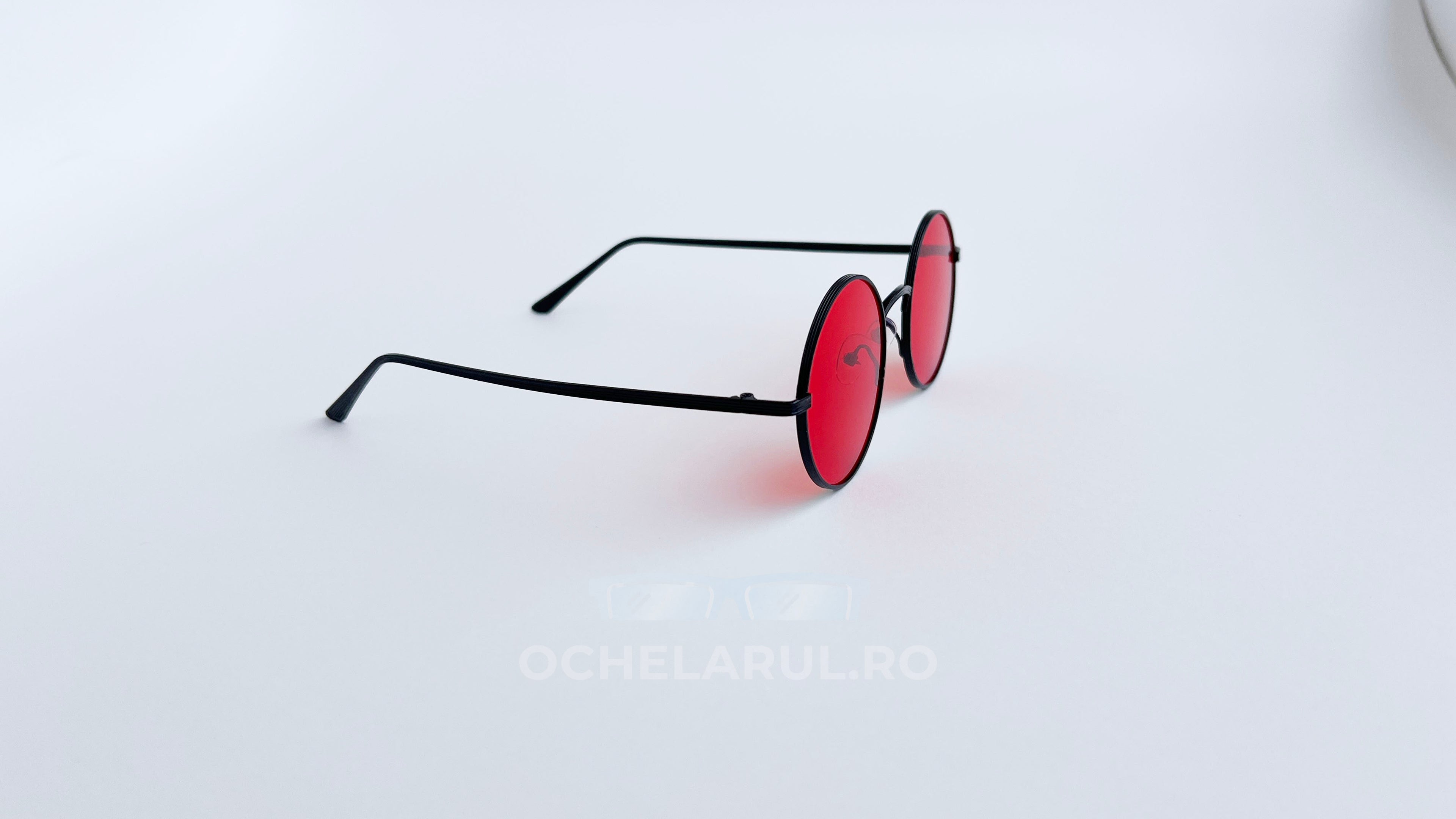 Ochelari de soare Rotunzi cu rame negre subțiri și lentile roșii, model modern unisex.