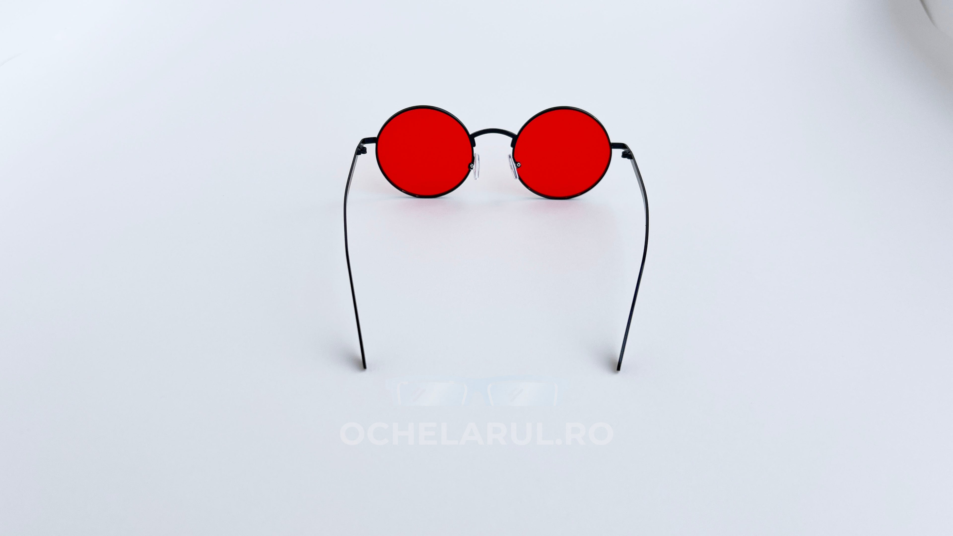 Ochelari de soare Rotunzi cu lentile roșii și rame subțiri negre, stil modern și minimalist.