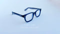 Rame ochelari Moscot Klutz Style în nuanță gri închis, cu lentile transparente, prezentate pe fundal alb.
