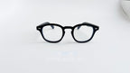 Rame ochelari Moscot Lemtosh Style negre cu lentile transparente așezate pe fundal alb simplu.