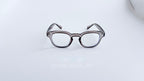 Rame ochelari Moscot Style cu aspect transparent gri, prezentate frontal pe fundal alb, lentile clare.